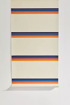 a piece of paper with multicolored stripes on it and a white wall in the background