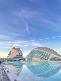 a large building sitting next to a swimming pool in front of a sky filled with clouds