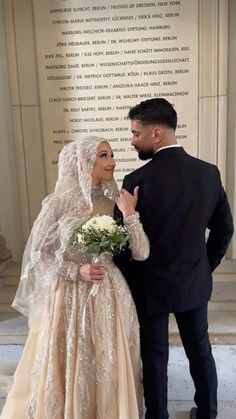 the bride and groom pose for a photo in front of a wall with words written on it