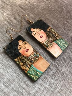 the earrings are made out of wood and have an image of a woman's face on