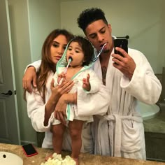 the man is taking a selfie with his two daughters while they both are wrapped in robes