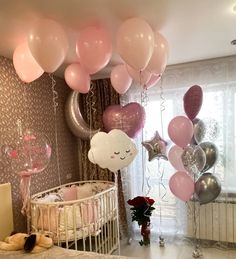 a baby's crib with balloons and stars hanging from the ceiling