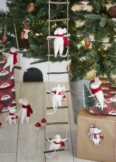 a christmas tree decorated with mice and presents under the ladder that is attached to it