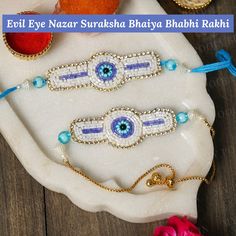 three evil eye bracelets with blue beads on a white plate next to pink flowers