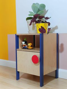 a toy house with a potted plant sitting on top of it and toys in the bottom drawer