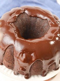 a chocolate bundt cake sitting on top of a white plate next to a blue napkin