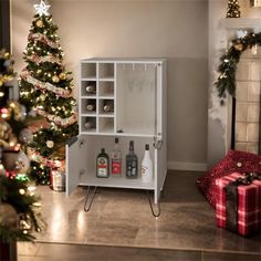 a christmas tree is next to a white cabinet with liquor bottles and presents on it