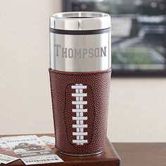 a football themed travel mug sitting on top of a table