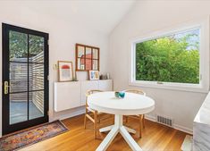 a white table and chairs in a small room with a large glass door leading to the outside