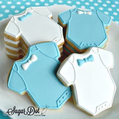 cookies decorated with blue and white onesuits are on a plate next to each other