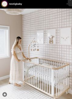 a woman standing next to a baby crib in a room with checkered walls