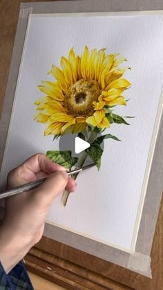 someone is painting a sunflower with watercolors