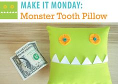 a green monster pillow sitting on top of a wooden table next to a dollar bill