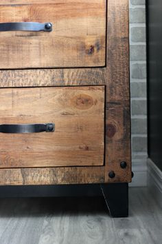 a wooden dresser with two drawers and black handles