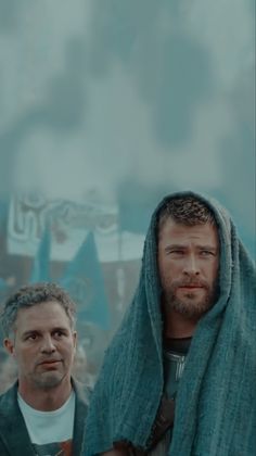 two men standing next to each other under a blanket