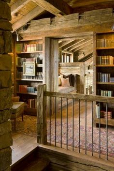 a room with bookshelves and stairs leading up to the second floor in an old log cabin