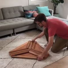 a man kneeling on the floor next to a couch and holding a piece of furniture