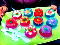 a person holding a tray with different colored cupcakes on top of each other