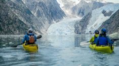 two people in kayaks paddling towards a glacier