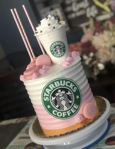 there is a starbucks cake with pink frosting on the top and two drinks on top