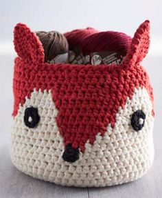 a crocheted basket with a red and white fox face