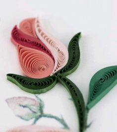 two paper flowers are sitting on a white table top, one is pink and the other is green