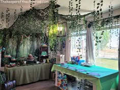 a room filled with lots of green plants and decorations on the walls, along with tables covered in cloths