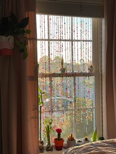 a bedroom window with beads hanging from it's sides and plants on the windowsill