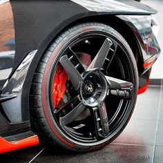 an orange sports car parked in a showroom with black rims and red brake pads