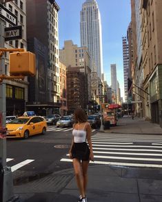 a woman is walking down the street in new york city, with skyscrapers in the background