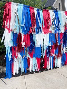 red, white and blue streamers are hanging on the side of a house with trees in the background