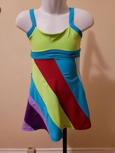 a mannequin wearing a multicolored tank top on a display stand in front of a wall