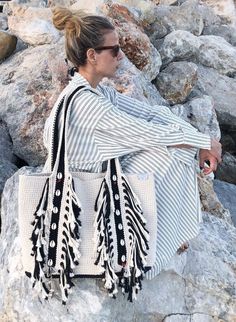 a woman sitting on top of a pile of rocks next to a white handbag