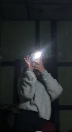 a woman taking a photo with her cell phone in front of a window at night