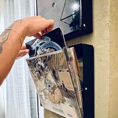 a person is holding an album in front of a wall mounted clock with the cover pulled off