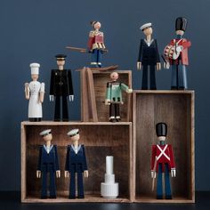 several wooden toy figures are arranged on top of each other, including one soldier and two sailors