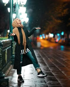 a woman standing in the rain with her arms outstretched