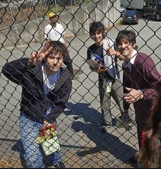 four young boys standing behind a chain link fence