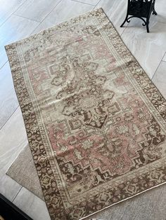 an old rug is laying on the floor next to a black chair and two chairs