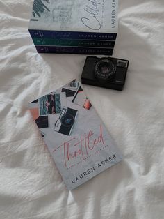 two books and a camera on a bed