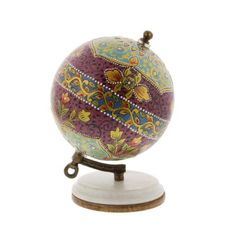 an ornately decorated globe on a wooden stand with a white base and brown accents