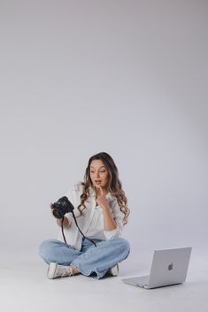 a woman sitting on the floor with a camera and laptop