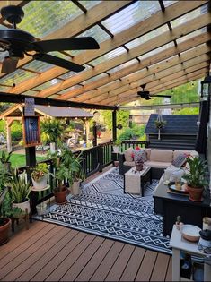 an outdoor living area with lots of plants and furniture on the deck, along with a ceiling fan