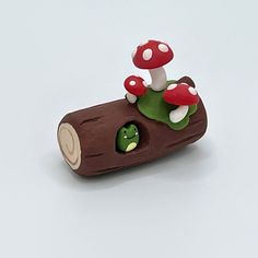 there is a small toy mushroom sitting on top of a piece of wood that has mushrooms growing out of it