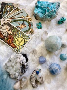 various crystals and tarot cards on a white furnishing area with blue hues