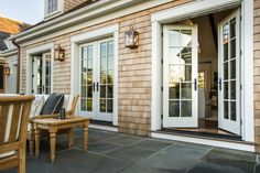 an outside patio with chairs, table and doors leading to the back yard area at dusk