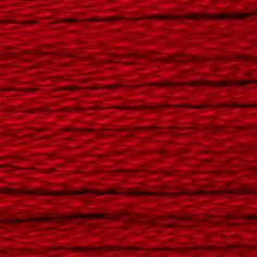 red yarn is spooled on a white surface