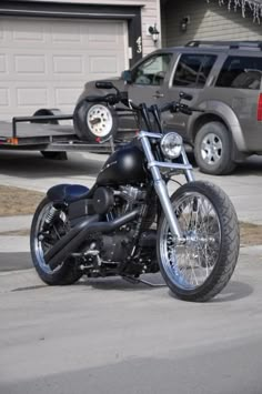 a black motorcycle parked in front of a house next to a gray truck on the street