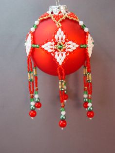 a red ornament hanging on a wall with beaded trimmings and beads