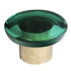 a close up of a green glass object on a white background with a gold base